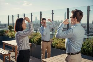 Pracownicy na tarasie biurowym, rozciągają się i patrzą na panoramę miasta
