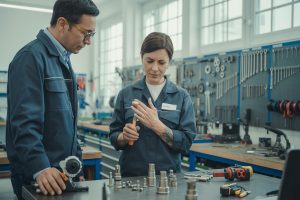 Pracownica warsztatu trzyma bolący nadgarstek podczas manualnej pracy przy podzespołach